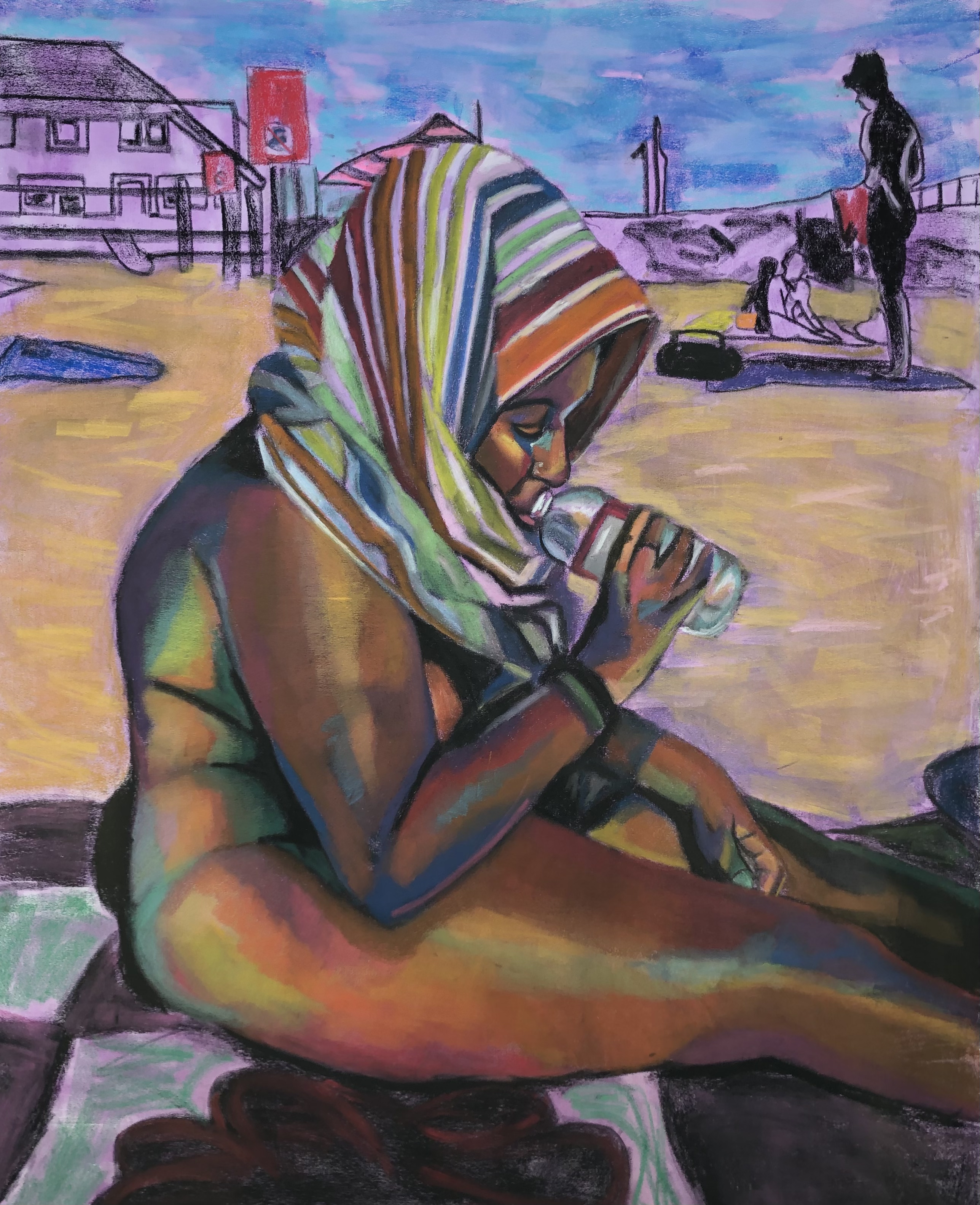 Artist sitting on the beach with a towel wrapped on her head sipping from bottle
