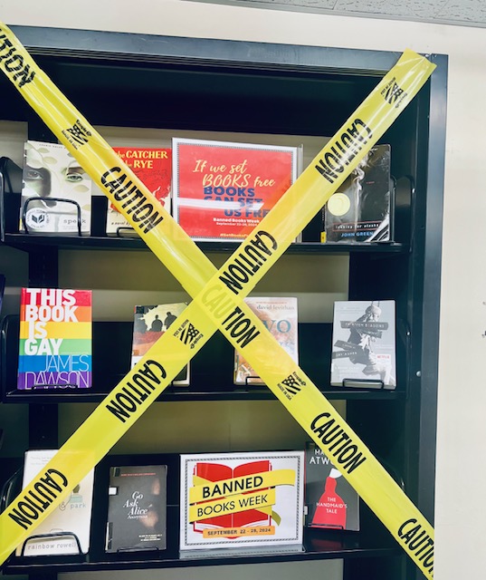 A display of banned books behind yellow caution tape.