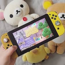 A gaming device with a purple background held up by a hand in front of stuffed animals