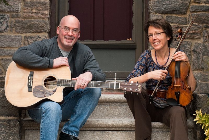 photo of Tom Socol holding guitar and Sarah Banks sitting on stairs