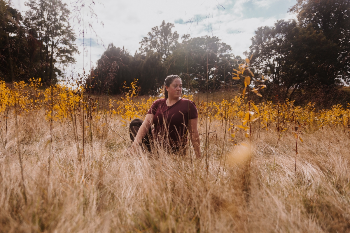 Image of Shannon in a Yoga pose in a field